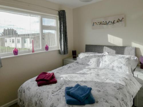 a bedroom with a bed with two towels on it at Willow Cottage in Kessingland