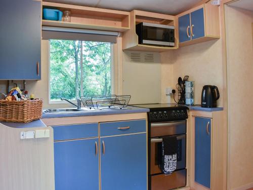 a kitchen with blue cabinets and a sink and a window at The Reme Villa in Scorton