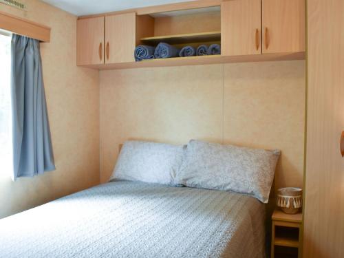 a small bedroom with a bed and wooden cabinets at The Reme Villa in Scorton