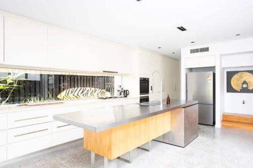 a kitchen with white cabinets and a wooden counter top at Casuarina Beachfront House - Hostie Properties in Casuarina