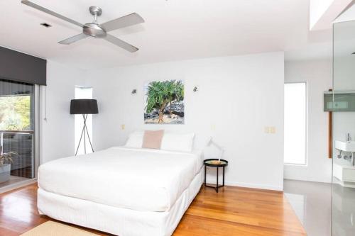 Casuarina Beachfront House - Hostie Properties في ساحة كاسوارينا: غرفة نوم بيضاء مع سرير أبيض ومروحة سقف