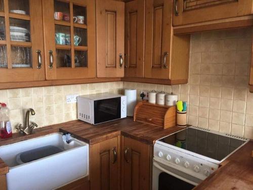 a kitchen with a sink and a microwave at Coastal Views Millport in Millport