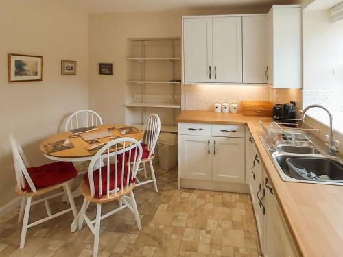 una cucina con tavolo, sedie e lavandino di Uk35716 - North Cottage a Teviothead