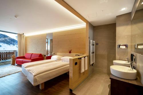 リヴィーニョにあるAlpen Resort Bivioのベッドルーム1室(ベッド1台付)、バスルーム(シンク付)
