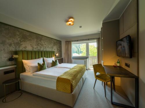Schlafzimmer mit einem Bett, einem Schreibtisch und einem Fenster in der Unterkunft Hotel Hennersberg in Wörgl