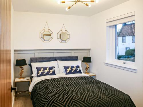 a bedroom with a bed and two lamps and a window at Forget Me Not Cottage in Culross