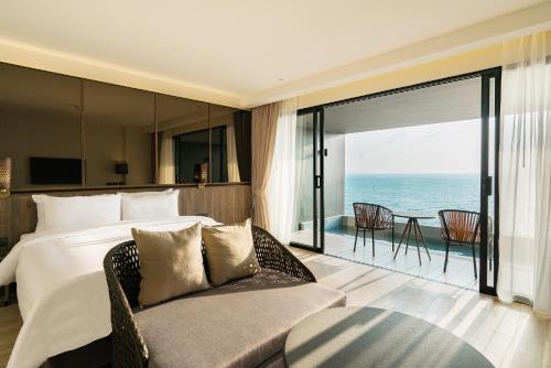 une chambre avec un lit et un canapé et une vue sur l'océan dans l'établissement Ana Anan Resort & Villas Pattaya, à Na Jomtien