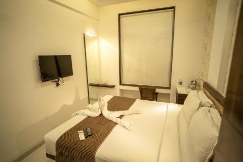 a hotel room with a bed and a television at Hotel SRI SRI EXECUTIVE KOLHAPUR NEAR MAHALAXMI TEMPLE in Kolhapur