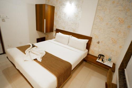 a bedroom with a large bed with white sheets and pillows at Hotel SRI SRI EXECUTIVE KOLHAPUR NEAR MAHALAXMI TEMPLE in Kolhapur