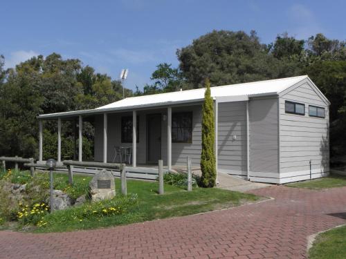 a white and blue house with a white fence at Lakeside Tourist Park in Robe