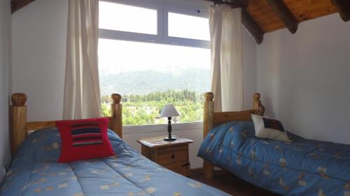 1 dormitorio con 2 camas y ventana grande en Cabañas Altos de Moquehue in 