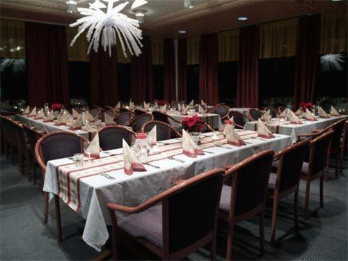 a group of long tables with chairs and a chandelier at Hotelli Haapakannel in Haapavesi