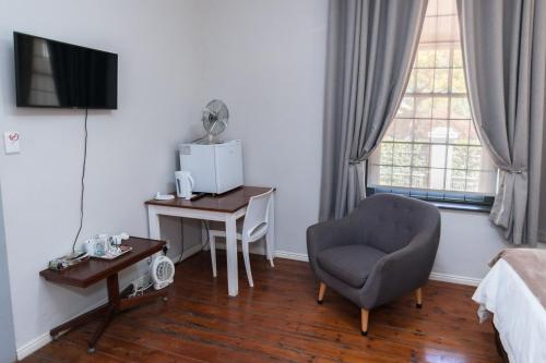 a hotel room with a chair and a desk and a window at Vlettershof Guest House in Robertson