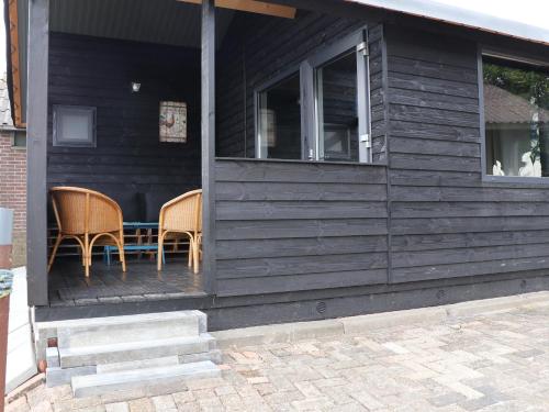 two chairs sitting on the porch of a black house at Hofstay195 in Achterveld