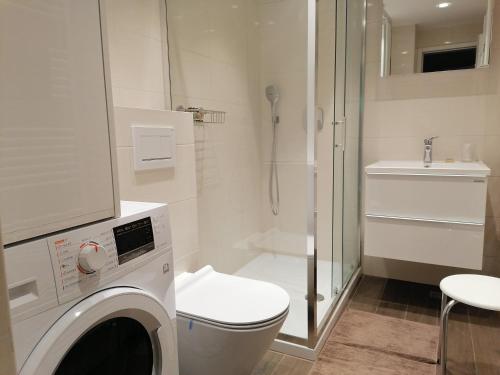 uma casa de banho com um WC, um chuveiro e uma máquina de lavar roupa em Apartment Green Oasis Zagreb em Zagreb