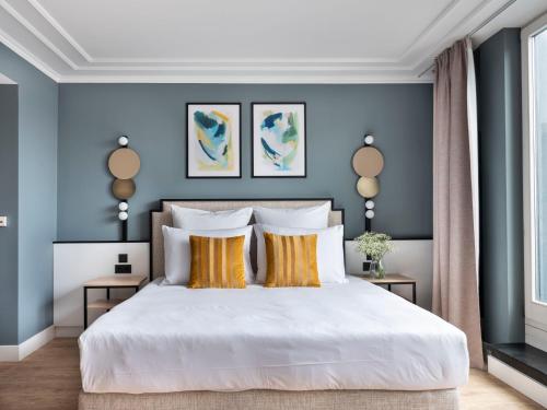 sypialnia z niebieskimi ścianami i białym łóżkiem z żółtymi poduszkami w obiekcie numa I Arc Rooms & Apartments w Berlinie