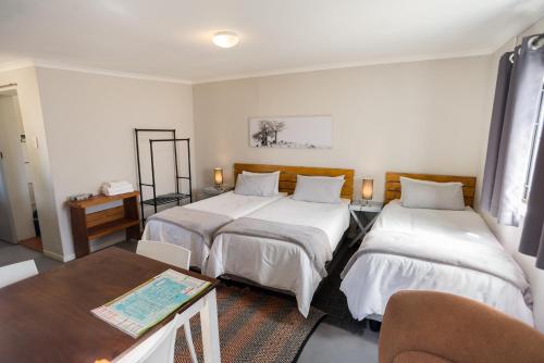 a room with two beds and a table and a table sidx sidx sidx at Vlettershof Guest House in Robertson