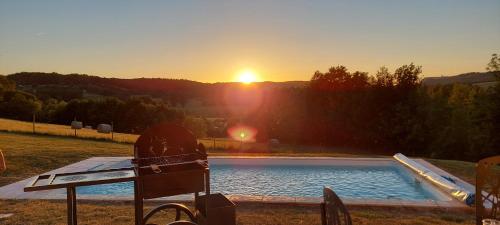 a swimming pool with a sunset in the background at Villa Puycelsienne in Les Barrières