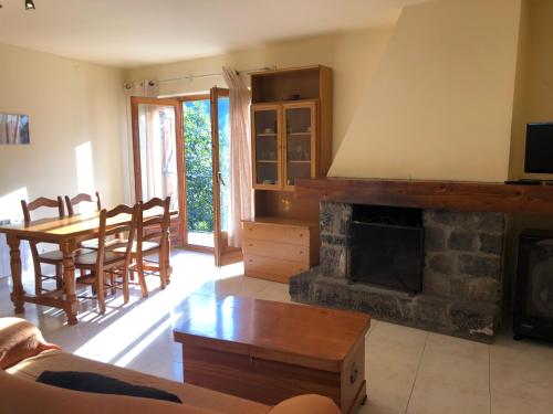 sala de estar con chimenea, mesa y sillas en Apartaments El Tarter, en Erill la Vall