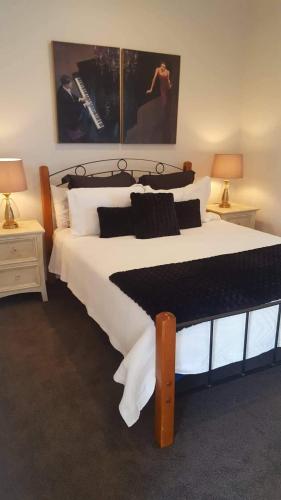 a bedroom with a large white bed with two lamps at Waterways Escape in Whitianga