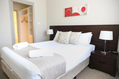 a bedroom with a large white bed with white pillows at Centrepoint Apartments Griffith in Griffith