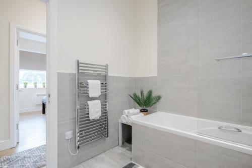 La salle de bains blanche est pourvue d'une baignoire et d'un lavabo. dans l'établissement Modern Elegant Luxury 1 bed flat Free parking, 
