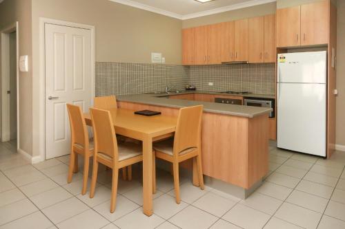 cocina con mesa de madera y nevera blanca en Centrepoint Apartments Griffith en Griffith
