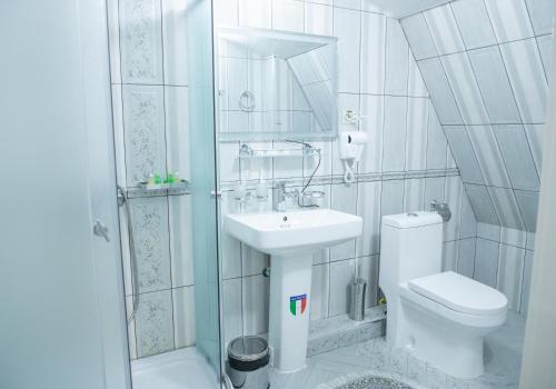 a white bathroom with a toilet and a sink at Renaissance Boutique Hotel in Samarkand