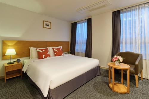 a hotel room with a large bed and a chair at Hotel Atrium Jongno in Seoul