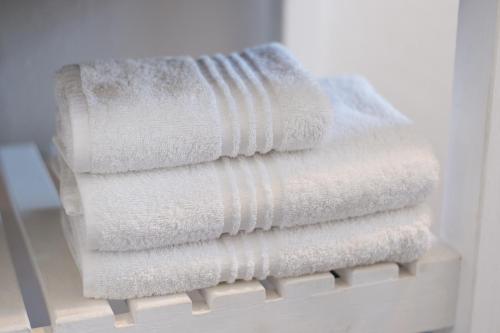 una pila de toallas blancas sentadas en un estante en Vlettershof Guest House, en Robertson