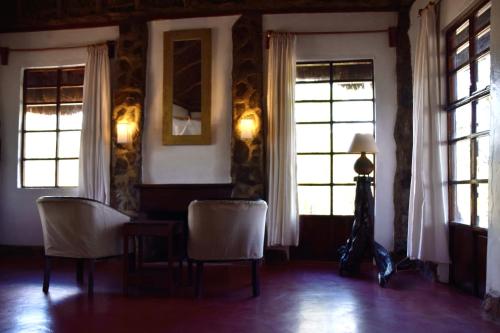 a room with two chairs and a table and two windows at Ngari Hill EcoLodge, Maralal - Kenya in Maralal