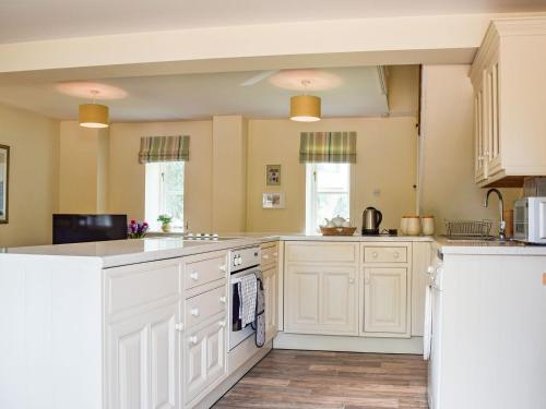 a kitchen with white cabinets and white appliances at Hall Piece Cottage in Olney
