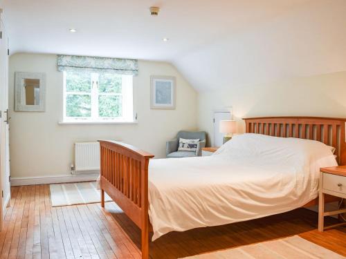 a bedroom with a large bed and a chair at Hall Piece Cottage in Olney