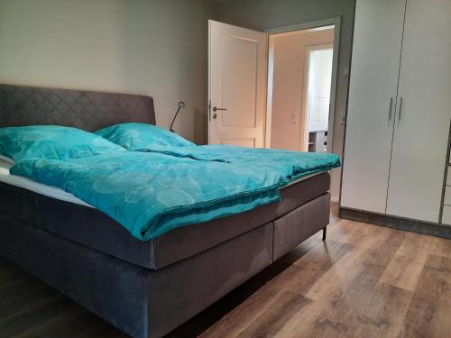 ein Bett mit blauer Decke in einem Schlafzimmer in der Unterkunft Valentinushof in Beckingen