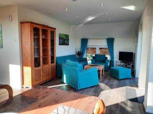 a living room with blue chairs and a television at Valentinushof in Beckingen