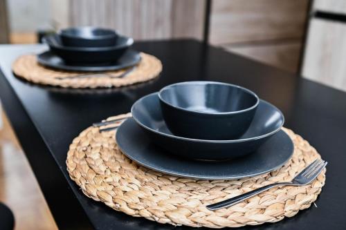 a table with two black bowls and plates on it at Cozy Apartment Plus in Novi Sad