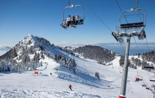 eine Gruppe von Menschen, die einen Skilift auf einem schneebedeckten Berg reiten in der Unterkunft Votre studio balnéo bien-être à la montagne in Thollon