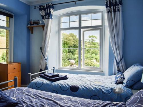 a blue bedroom with a bed and a window at Lower Lodge in Bugle