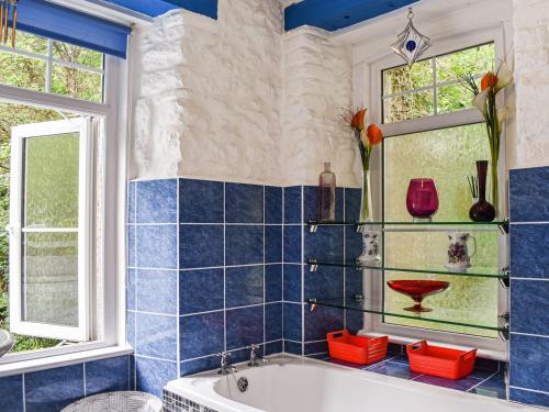 a blue tiled bathroom with a tub and two windows at Lower Lodge in Bugle