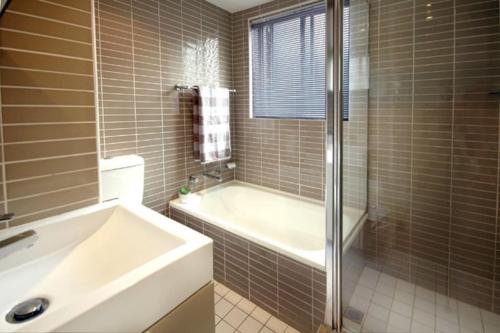 y baño con bañera, ducha y lavamanos. en VELLY-Modern Light 2BR Moments from Clovelly Beach, en Sídney