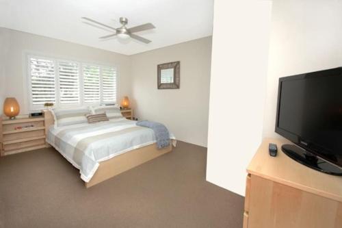 a bedroom with a bed and a flat screen tv at VELLY-Modern Light 2BR Moments from Clovelly Beach in Sydney