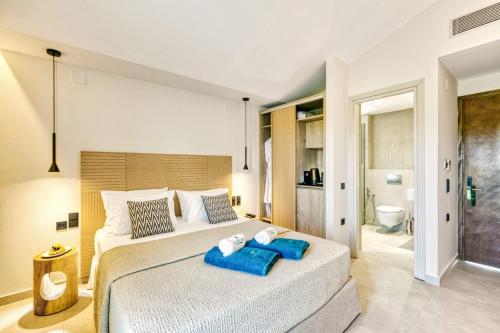 a bedroom with a large bed with two blue towels on it at Hidden Cove Corfu in Kontokali
