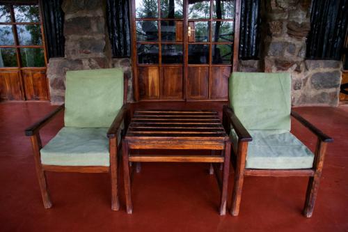 two chairs and a wooden table and a table and chairs at Ngari Hill EcoLodge, Maralal - Kenya in Maralal