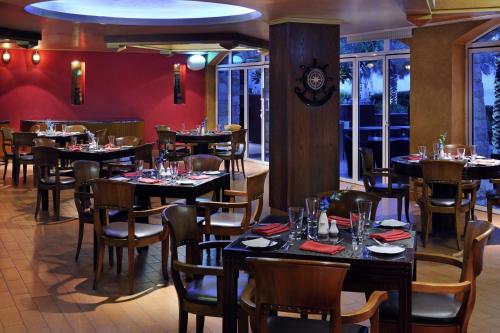 a restaurant with tables and chairs in a room at Mövenpick Hotel & Resort Al Bida'a in Kuwait