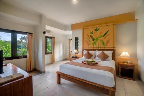 a bedroom with a large bed and a television at Uma Dana Ubud in Ubud