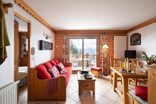 a living room with a red couch and a table at Résidence Pierre & Vacances Premium Le Roselend in Arc 1800