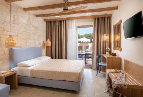 a hotel room with a bed and a television at Kseynasa Suites in Nikiti