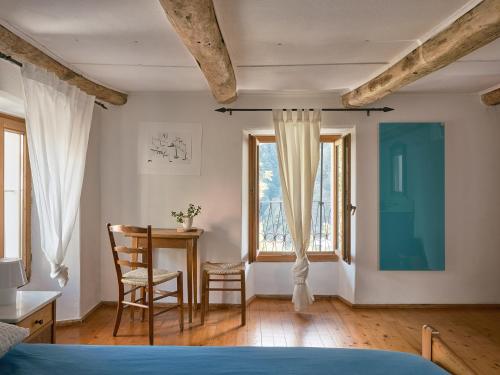 1 dormitorio con mesa, silla y ventana en Osteria Grütli con alloggio en Borgnone