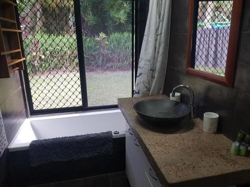 baño con lavabo, bañera y ventana en Rustic Retreat, en Jaggan
