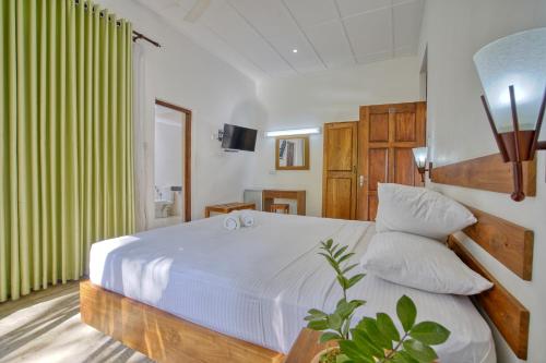 1 dormitorio con cama blanca y cortinas verdes en Raddegoda Walawwa Kurunegala, en Ridigama